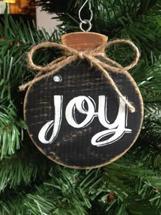 a wooden ornament hanging from a christmas tree with the word joy written on it