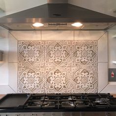 a stove top oven sitting inside of a kitchen next to a wall covered in tile