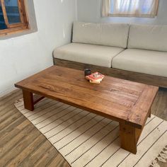 a wooden table sitting on top of a hard wood floor next to a white couch