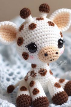 a small crocheted giraffe sitting on top of a blanket