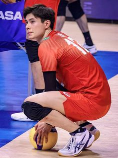 a man kneeling down on top of a basketball ball