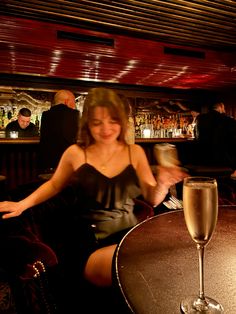 a woman sitting at a table with a glass of wine