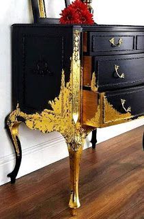 an ornate black and gold dresser with red flowers on it's top, in front of a white wall