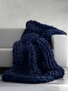 a knitted blanket sitting on top of a couch next to a white sofa with the words knitting blanket blue