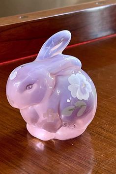 a glass rabbit figurine sitting on top of a wooden table