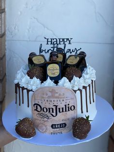 a birthday cake with chocolate covered strawberries and bottles of booze on the top