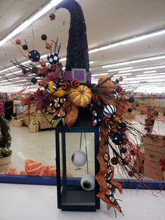 a lighted lantern with decorations on it in a large room filled with pumpkins and other items