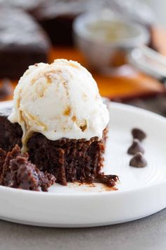 a piece of chocolate cake with ice cream on top is sitting on a white plate