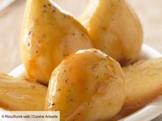 three pieces of pears on a plate with some sauce and bread in the background