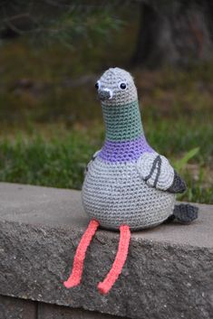 a crocheted bird sitting on top of a cement block