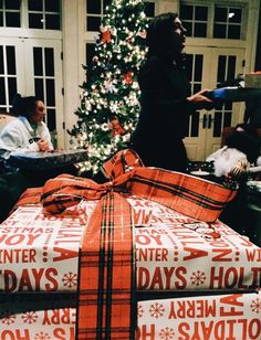 presents wrapped in red and white paper are stacked on top of each other near a christmas tree