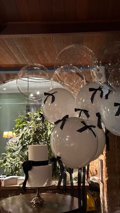 some balloons are hanging from the ceiling in front of a table with a cake on it