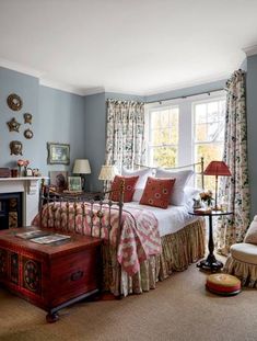 a bed room with a neatly made bed next to a window and a fire place