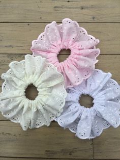 three scrunffle hair ties in white, pink and blue on a wooden surface