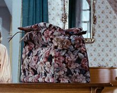 a woman sitting at a table in front of a purse on top of a dresser