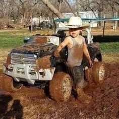 a little boy that is standing in the dirt with a truck on it's back