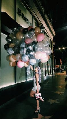 a woman is holding balloons in front of a store