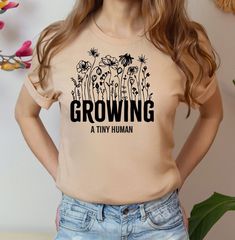 a woman wearing a t - shirt that says growing, with flowers on the front