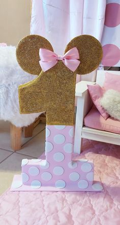 a pink and gold minnie mouse cake topper with a bow on it's head