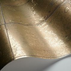 a close up view of a metal surface with gold leafy paint on the edges