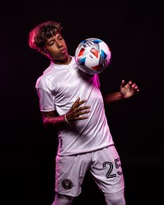 a young man holding a soccer ball in his hands