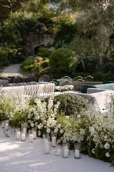 white flowers and candles are lined up on the table in front of an outdoor seating area