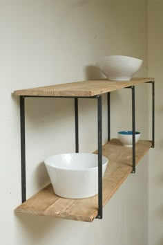 two wooden shelves with bowls on them against a white wall and one shelf holding a bowl