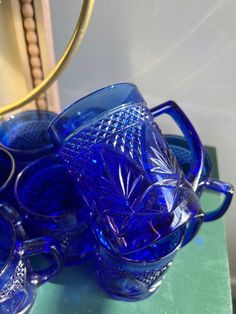 blue glass dishes and cups are sitting on a table