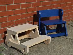 two children's wooden toys sitting next to each other on the ground near a brick wall