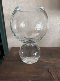 a clear glass vase sitting on top of a wooden table