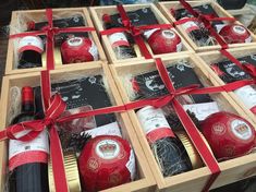 several bottles of wine are wrapped in red ribbon and placed inside wooden boxes with bows