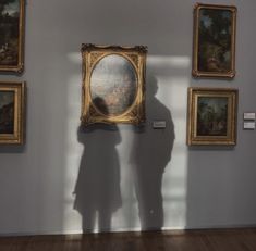 the shadow of a person standing in front of paintings