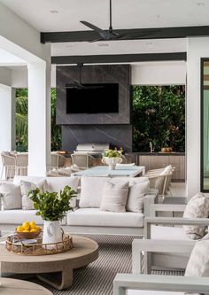 a living room filled with white furniture and a flat screen tv mounted to the wall