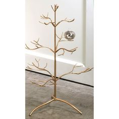 a gold metal tree with two ornaments on it's branches and a silver ball hanging from the top