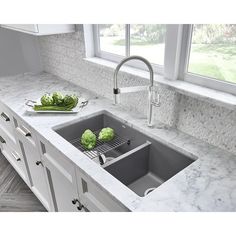 a kitchen sink with two green vegetables on the counter top next to an open window