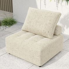 a beige couch sitting on top of a white tile floor next to a potted plant