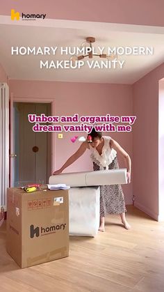 a woman standing in front of a box on top of a wooden floor next to a bed