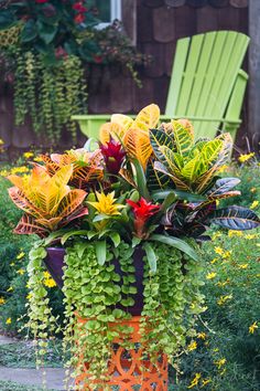 a tall vase filled with lots of different types of flowers next to a green lawn chair