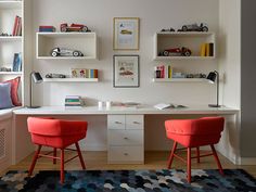 two red chairs sitting in front of a white desk with bookshelves on it