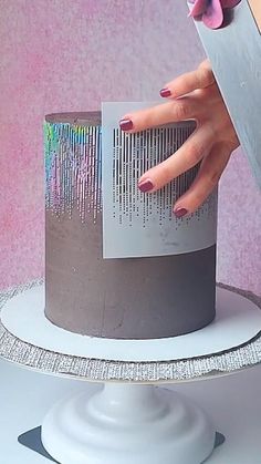 a woman's hand on top of a cake with a knife sticking out of it