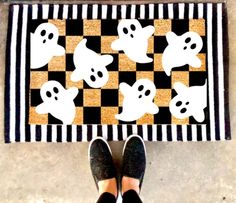 a person standing in front of a black and white rug with ghost faces on it