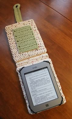 an electronic device sitting on top of a wooden table covered in crocheted material