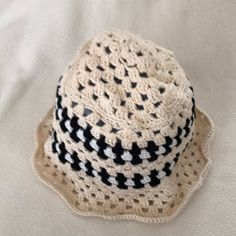 a crocheted hat sitting on top of a white bed cover with black and white designs