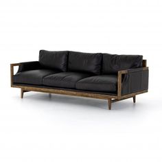 a black leather couch sitting on top of a white floor next to a wooden frame