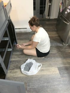 a woman sitting on the floor in front of an oven