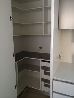 an empty pantry with white cabinets and drawers