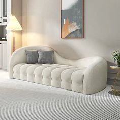 a white couch sitting on top of a rug in a living room next to a lamp