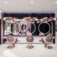 the interior of a salon with pink chairs and round lights hanging from the ceiling above