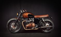 a brown and black motorcycle parked in front of a dark background