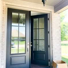 a black front door with two sidelights and a box on the porch outside it